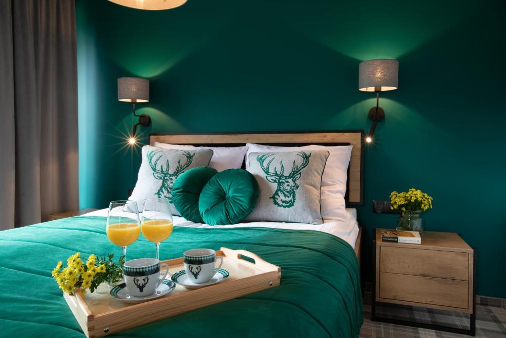 a green bedroom with a bed with a tray with glasses of orange juice at Apartamenty Koziniec in Zakopane