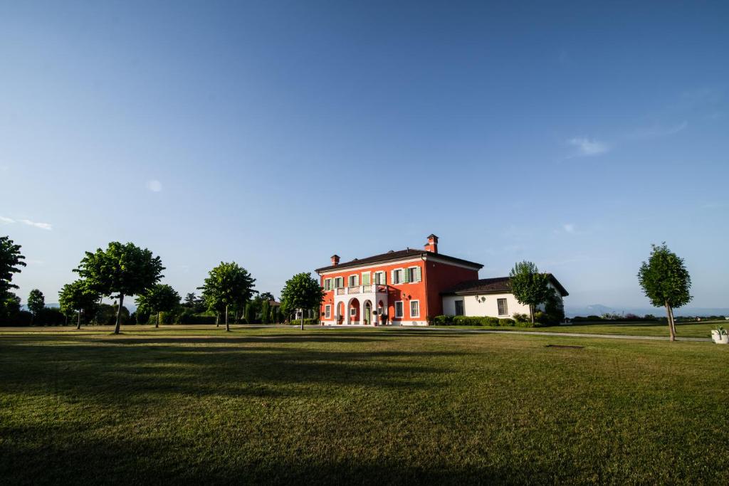 Una gran casa roja y blanca con un gran campo de hierba. en Villa San Pietro en Desenzano del Garda