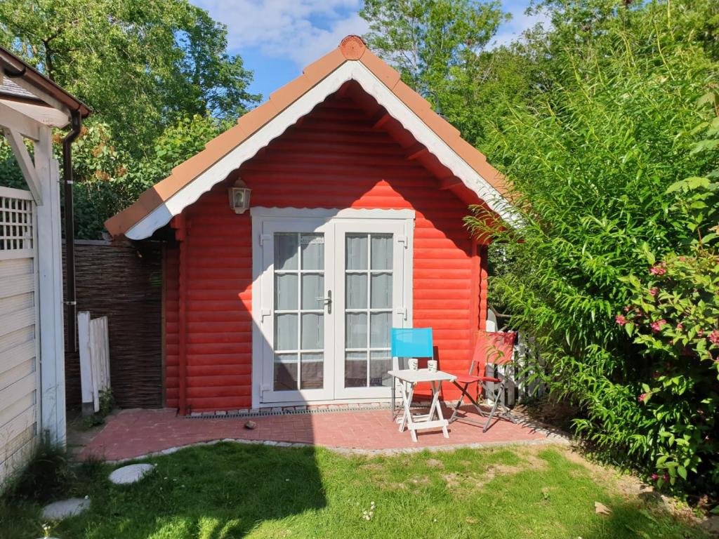 a red cottage with a table and a blue chair at Tinyhouse am Fluss in Otterndorf