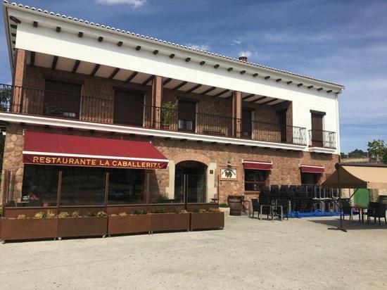 un gran edificio de ladrillo con un balcón en la parte superior. en Hostal La Caballeriza en Malpartida de Cáceres
