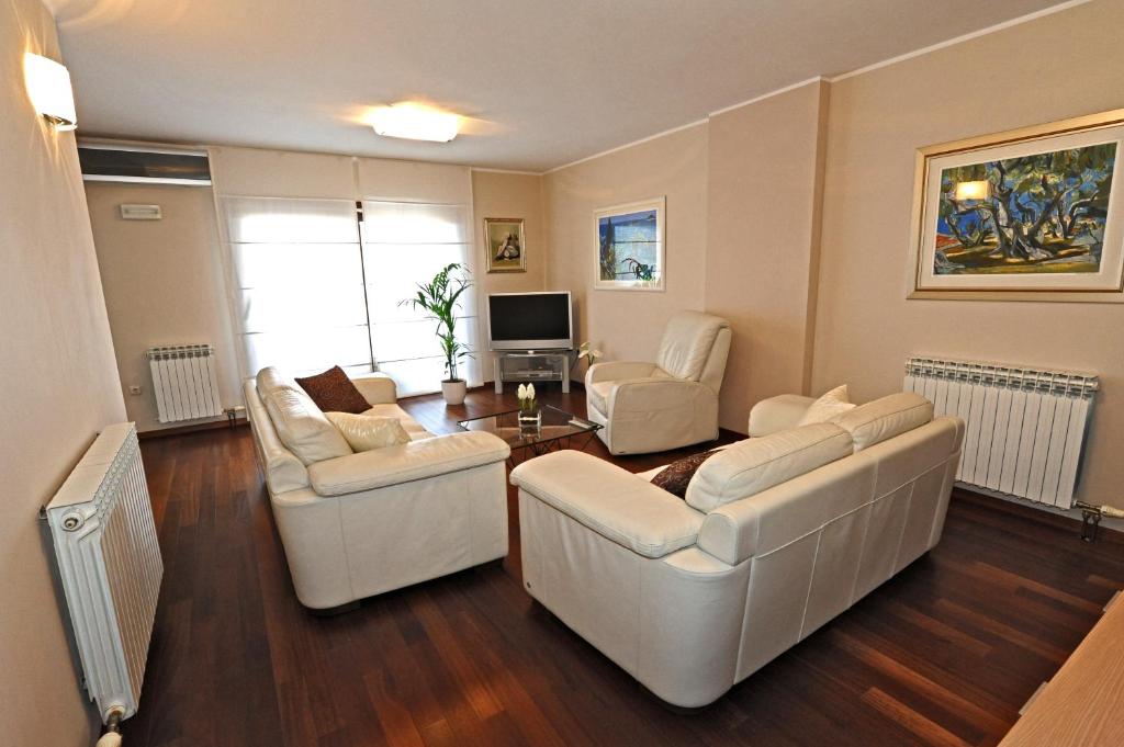 Sala de estar con 2 sofás blancos y TV en Apartments Villa Violet, en Zadar