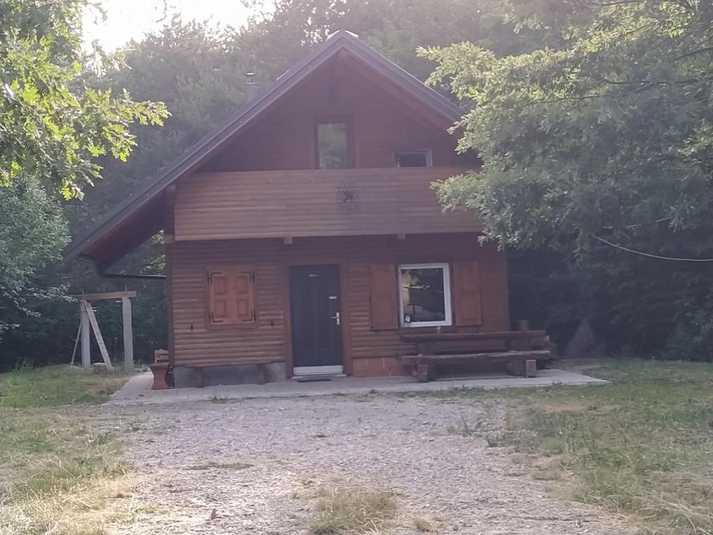 una cabaña de madera con un banco delante en Podklanci, en Knežak