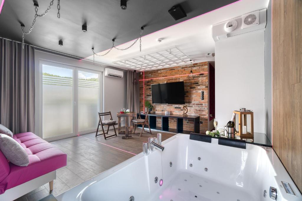 a large bathroom with a tub and a pink couch at Relaxroom in Reda