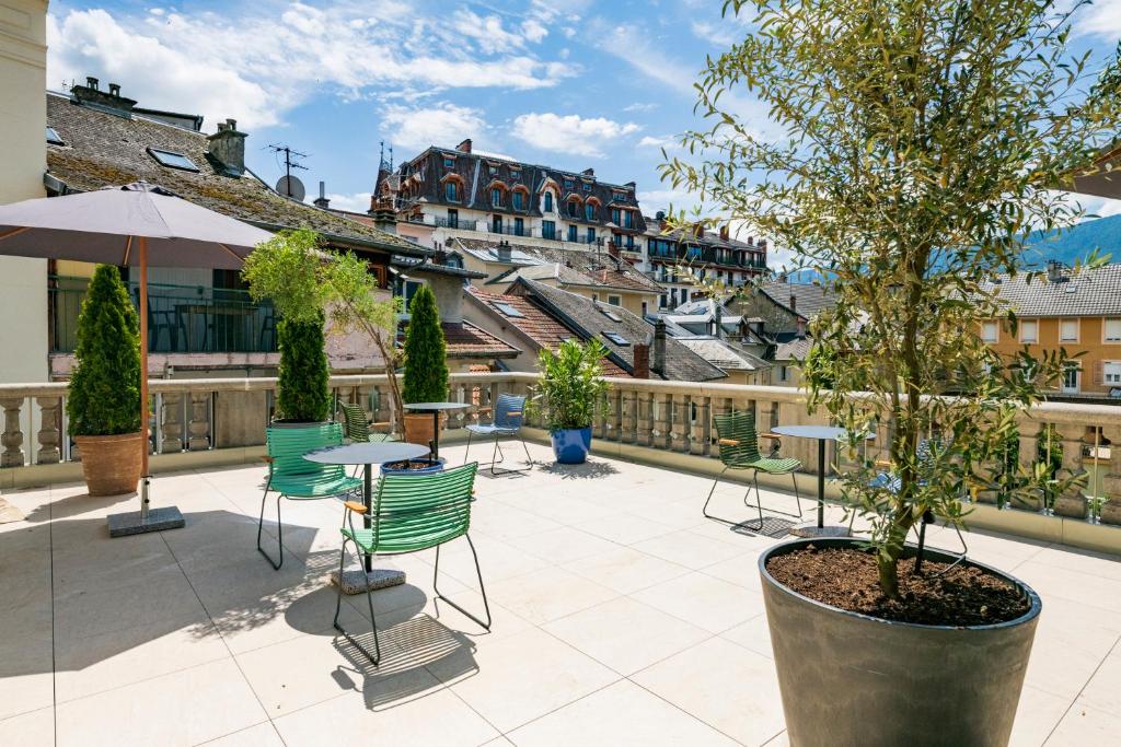 een patio met stoelen en tafels en een boom bij Belle Epoque in Aix-les-Bains