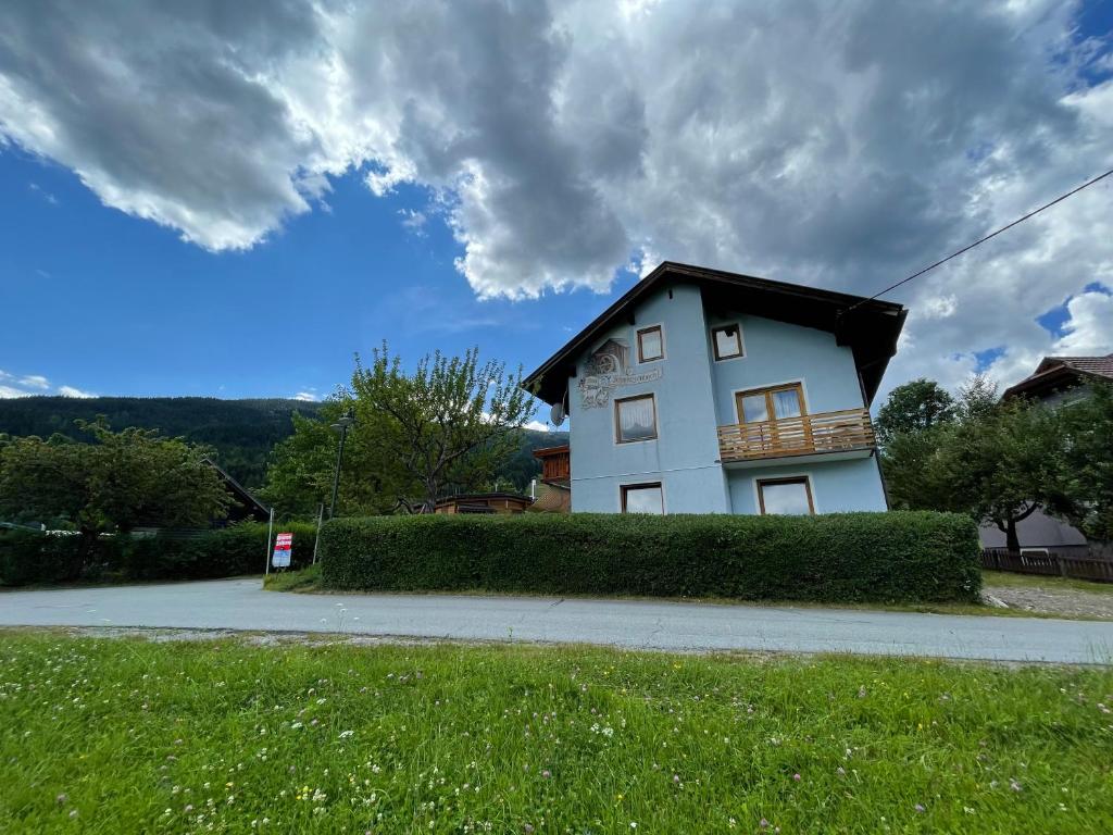 ein weißes Haus mit schwarzem Dach auf einer Straße in der Unterkunft Haus Schwarzenbach in Weissbriach