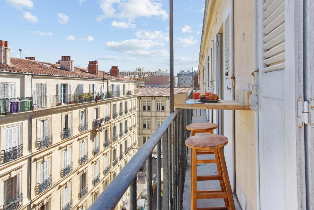 un tabouret sur un balcon avec vue sur les bâtiments dans l'établissement Appartement Joliette - Welkeys, à Marseille