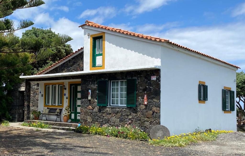 una pequeña casa blanca con persianas verdes en Casa da Costa en Madalena