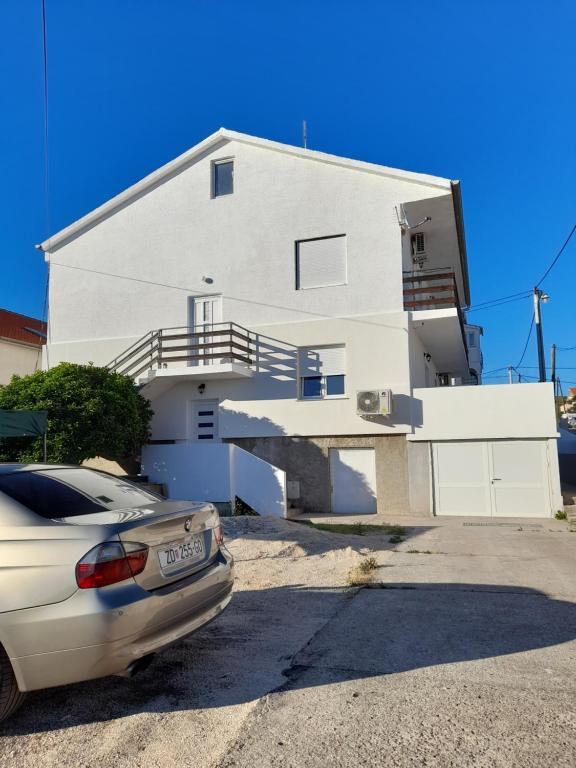 una casa blanca con un coche aparcado delante de ella en Apartment Mario, en Zadar