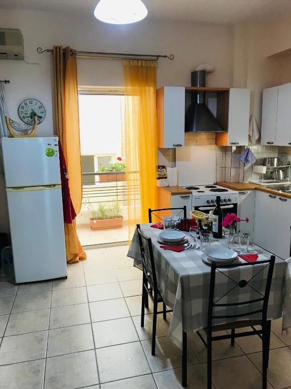 a kitchen with a table and a white refrigerator at Cozy Apartment Near City Center in Preveza