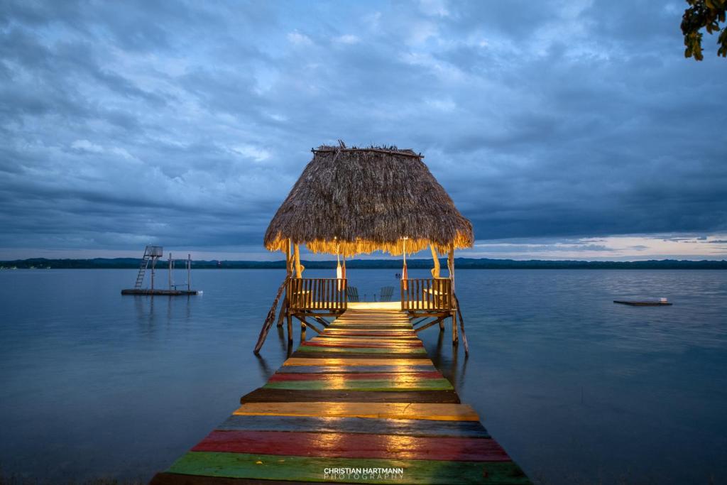 un quai avec une cabane en paille sur l'eau dans l'établissement Hotel Gringo Perdido, à El Remate