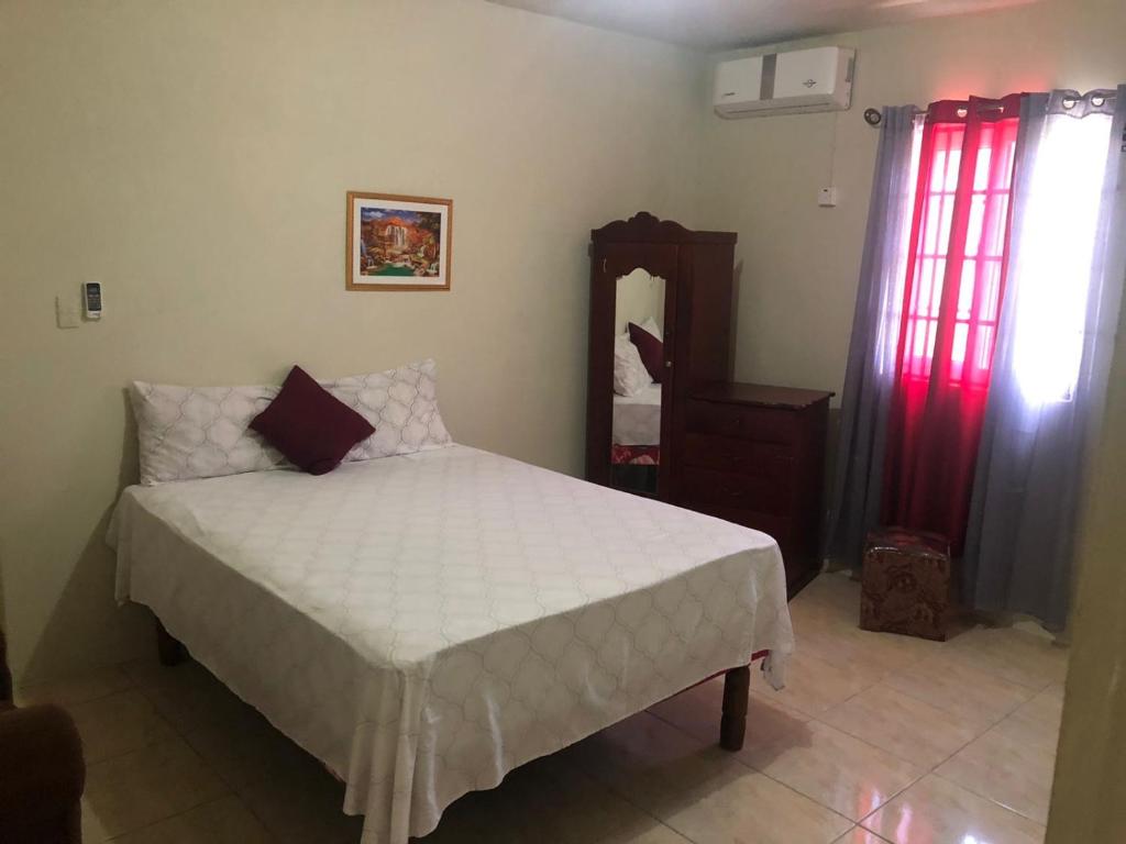 een slaapkamer met een bed, een dressoir en een spiegel bij ApartmentsWestvillage 2bedroom in Montego Bay