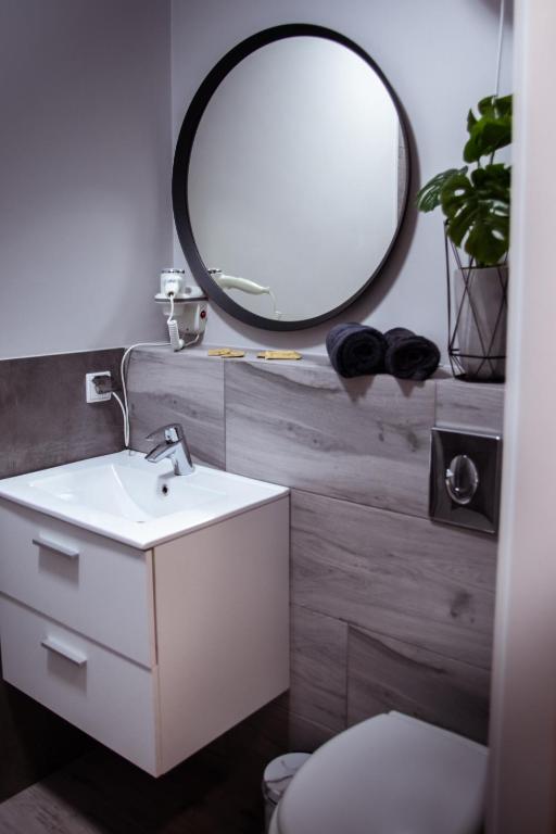 łazienka z białą umywalką i lustrem w obiekcie Apartamenty Długa 6 w Bydgoszczy