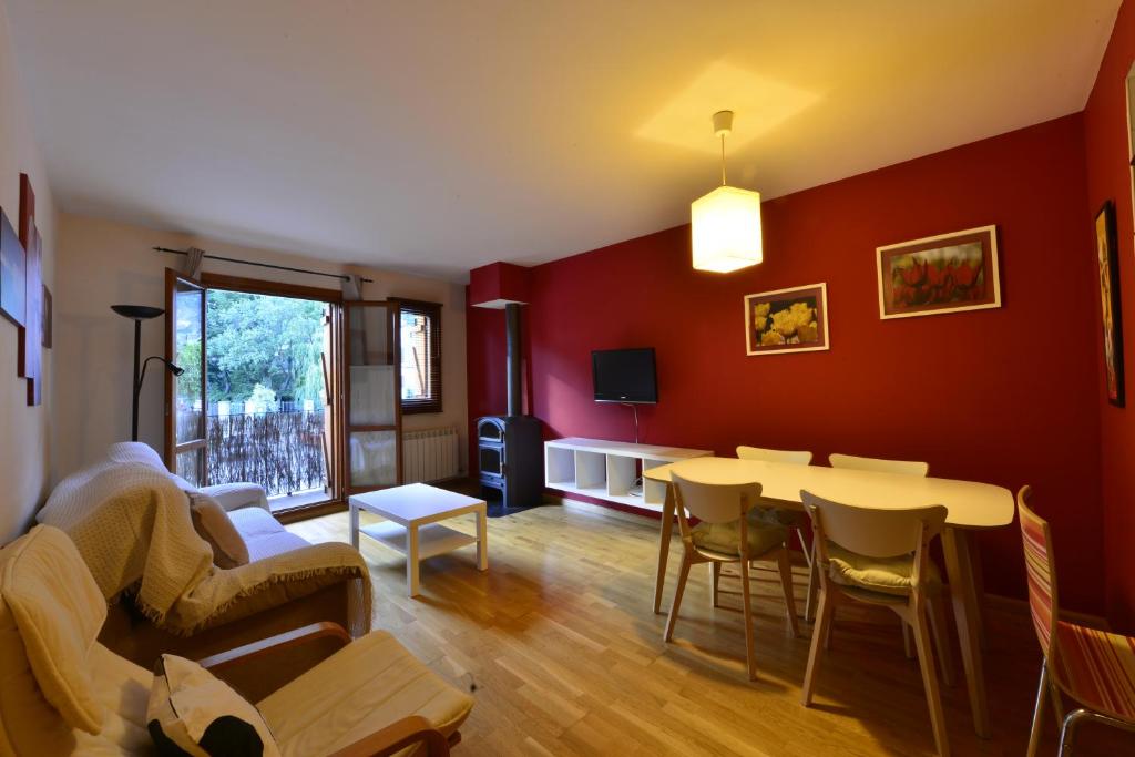 a living room with red walls and a table and chairs at El Mirador de las Tucas in Benasque