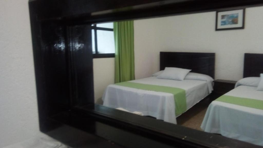 a reflection of a bedroom with two beds in a mirror at Hotel D'Lina Princess Suites in San Cristóbal de Las Casas