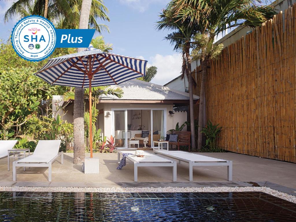 a patio area with a lawn chair and a white umbrella at Malibu Koh Samui Resort & Beach Club - SHA Extra Plus in Chaweng