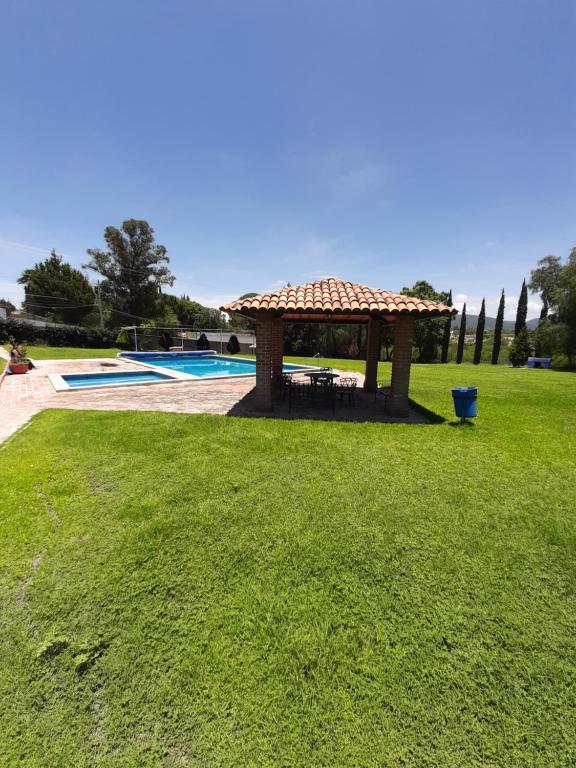 een prieel in het gras naast een zwembad bij Villa Centenario exclusivo Familias in Tequisquiapan