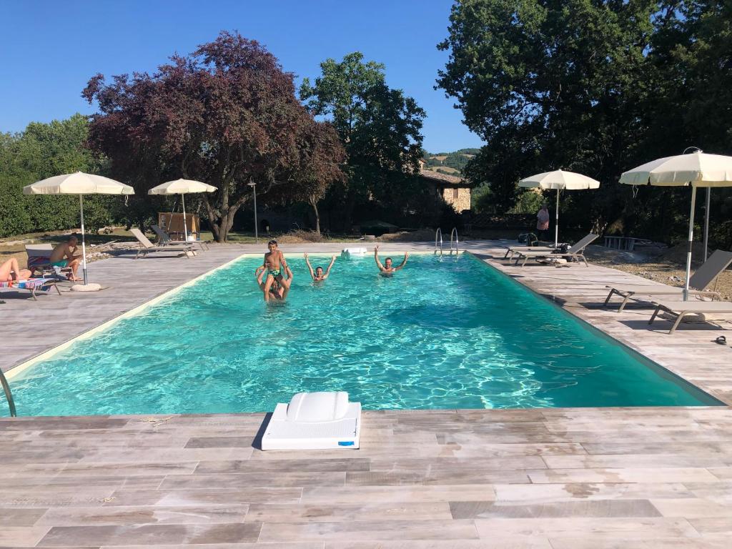 a woman is swimming in a pool with a blue umbrella at Hotel Giogliano in Radicondoli
