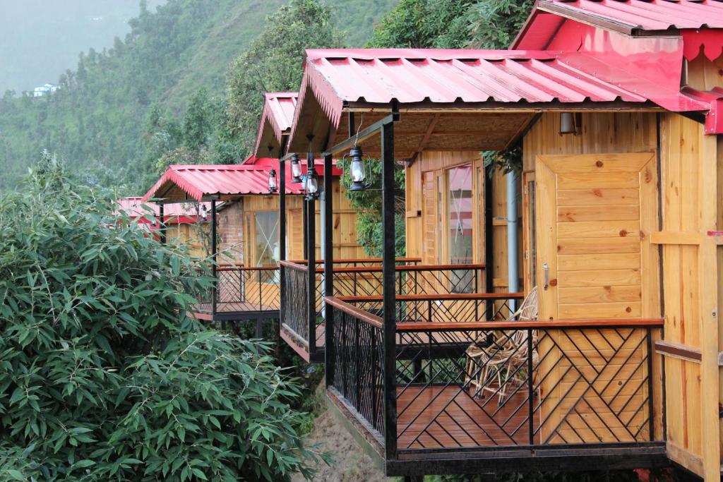a row of wooden houses with red roofs on a hill at Royal Cliff Resorts in Nainital
