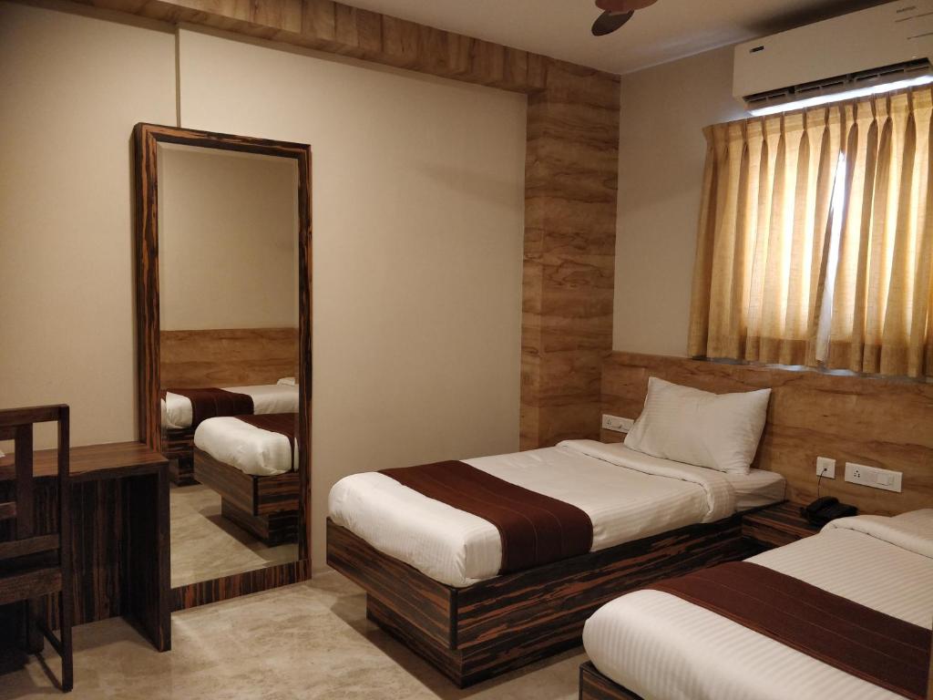 a hotel room with two beds and a mirror at Icon Residency in Chennai