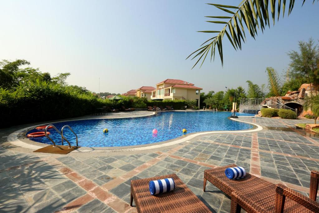 a swimming pool with two chairs and a playground at Resort De Coracao - Corbett , Uttarakhand in Rāmnagar