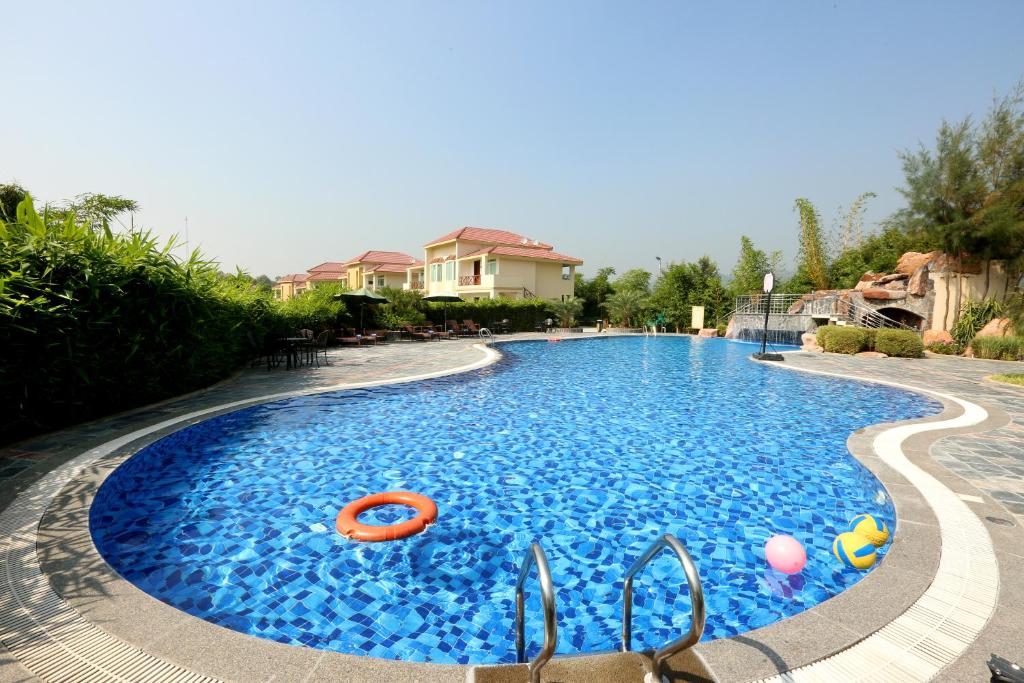 a swimming pool with blue water in a yard at Resort De Coracao - Corbett , Uttarakhand in Rāmnagar