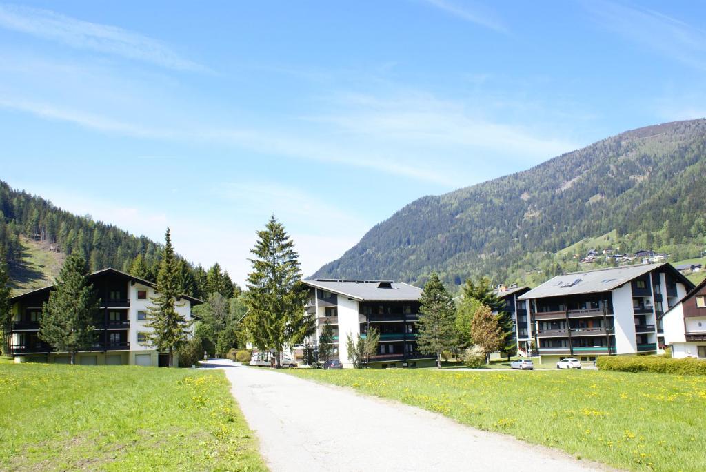 eine Straße, die zu einem Ferienort mit Bergen im Hintergrund führt in der Unterkunft Appartementanlage Bach in Bad Kleinkirchheim