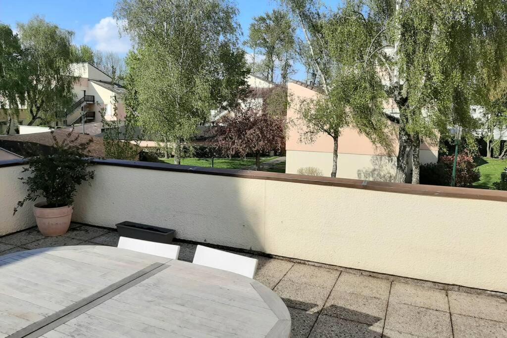 eine Terrasse mit einem Tisch und einer weißen Wand in der Unterkunft Appartement au lac du chateau in Flers-lez-Lille