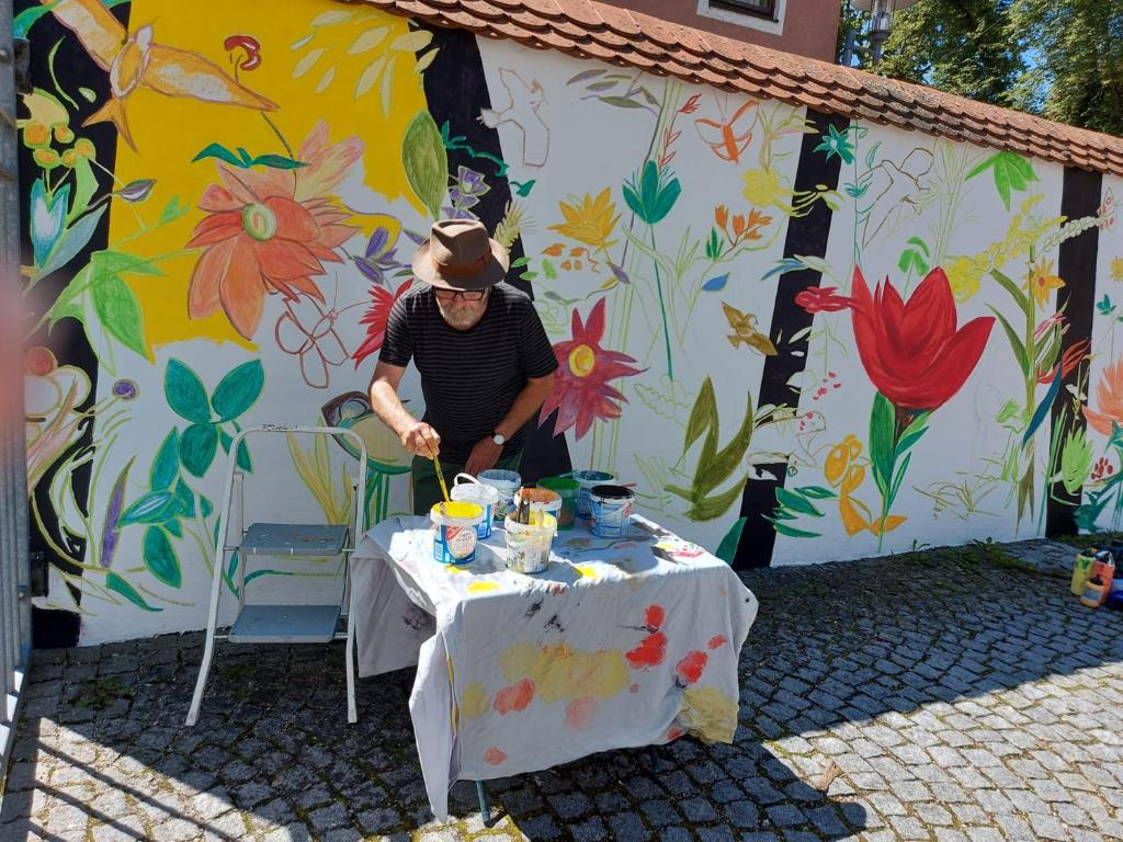 a man standing at a table in front of a mural at Hotel Bergbauer in Neuburg an der Donau