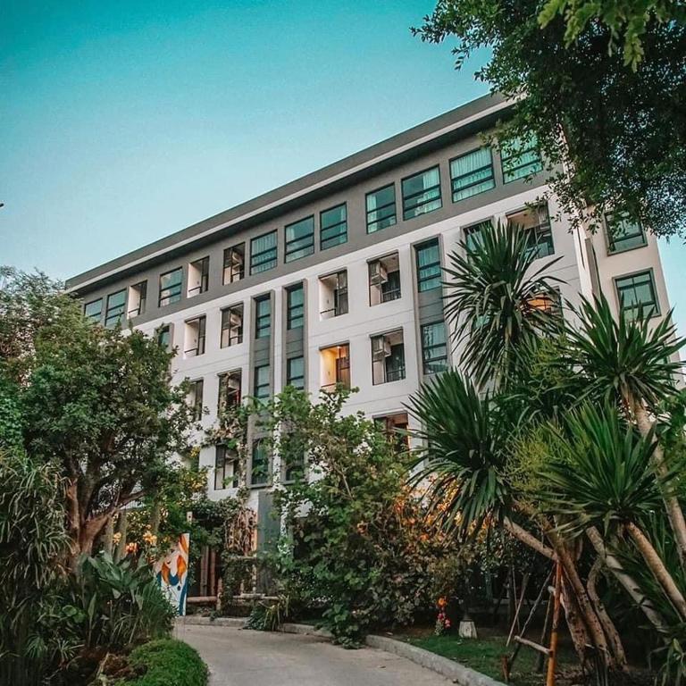 a large white building with palm trees in front of it at Bangkok Oasis Hotel in Bangkok