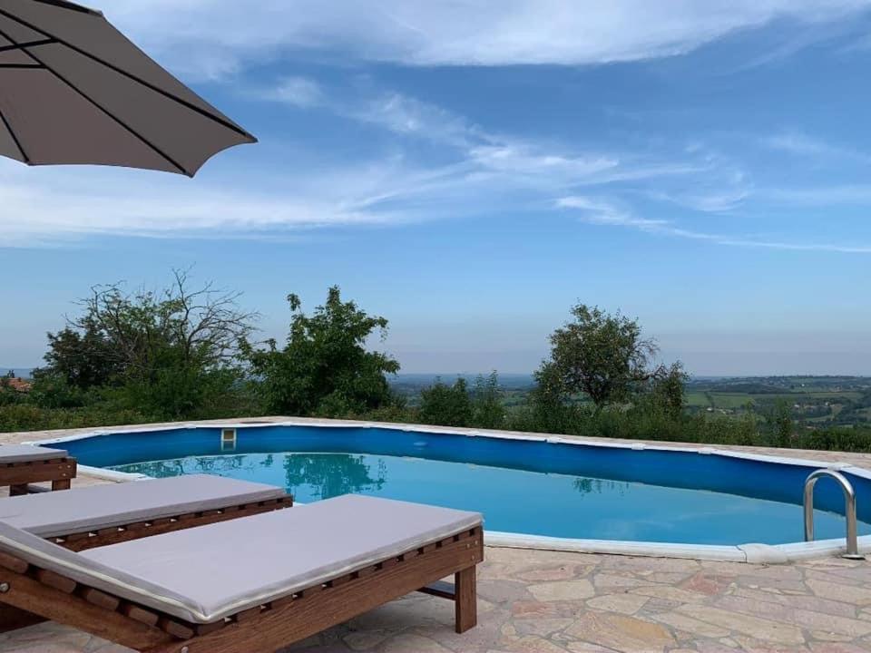 a pool with an umbrella and a table and chairs at Talin Raj in Arandjelovac