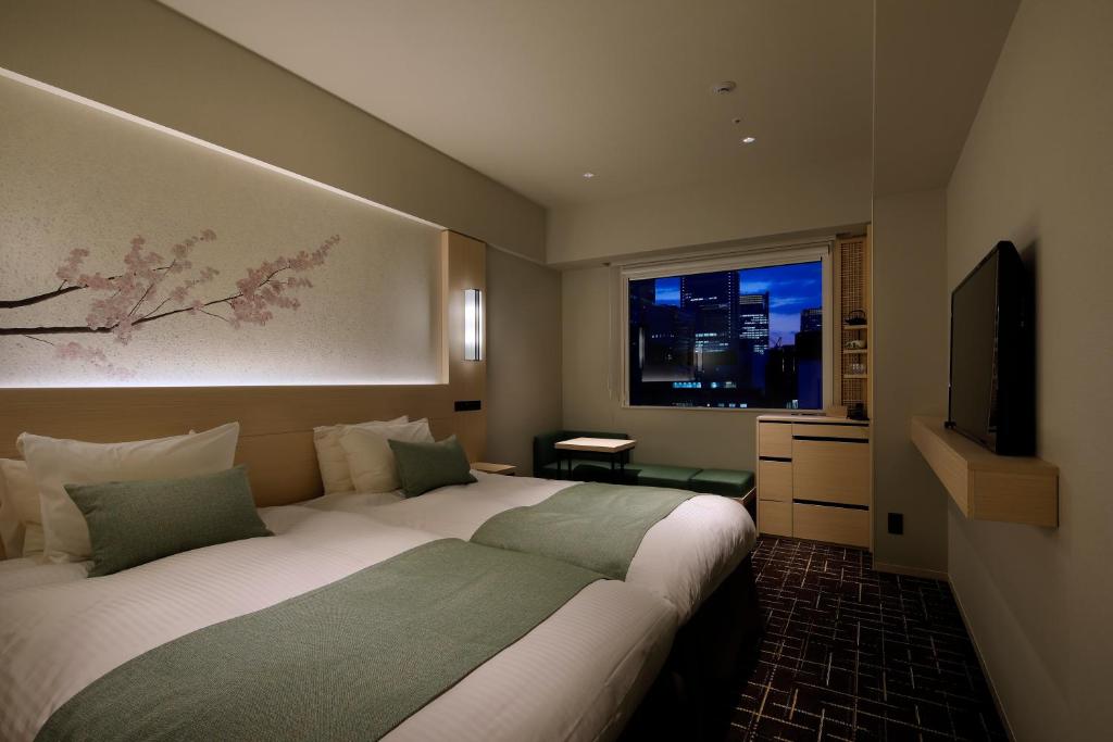東京にあるホテル八重の翠東京のベッド2台とテレビが備わるホテルルームです。
