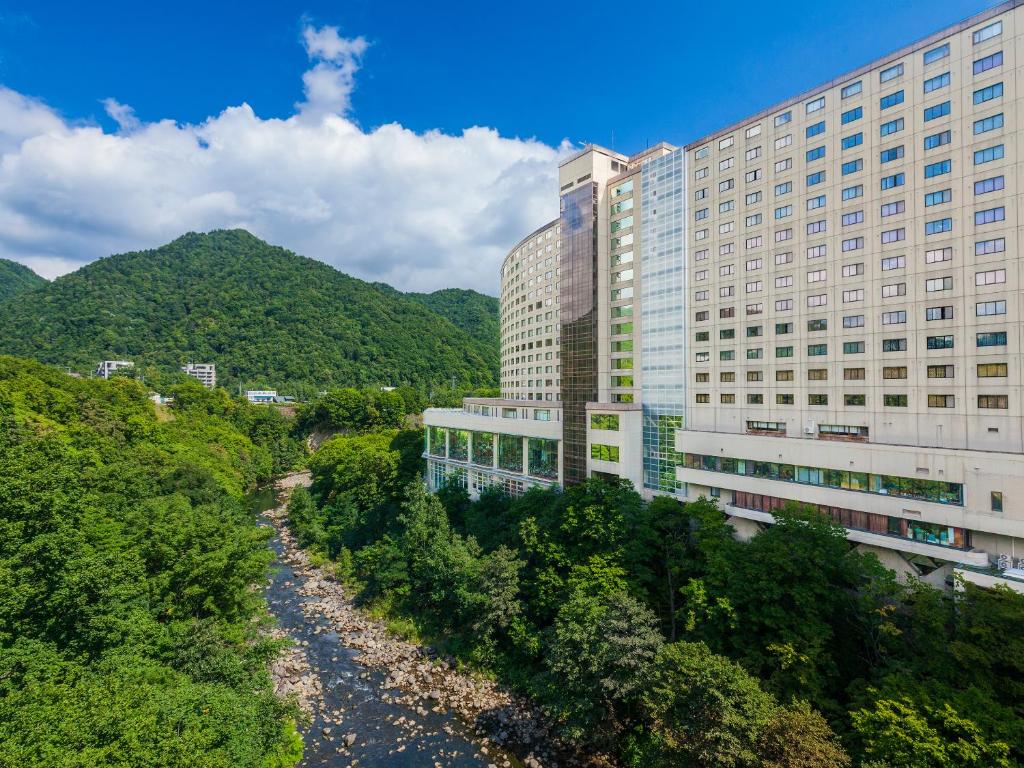 un edificio accanto a un fiume accanto a un edificio di Jozankei View Hotel a Jozankei