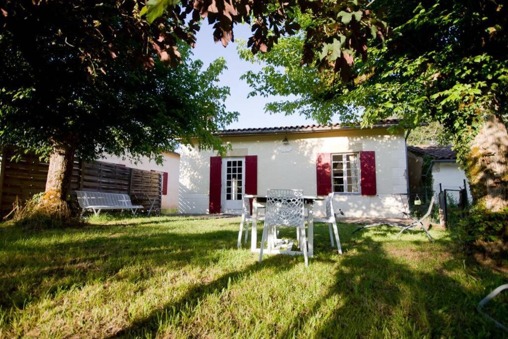 una casa bianca con un tavolo in cortile di Gîte Aux Tuileries a Noaillan