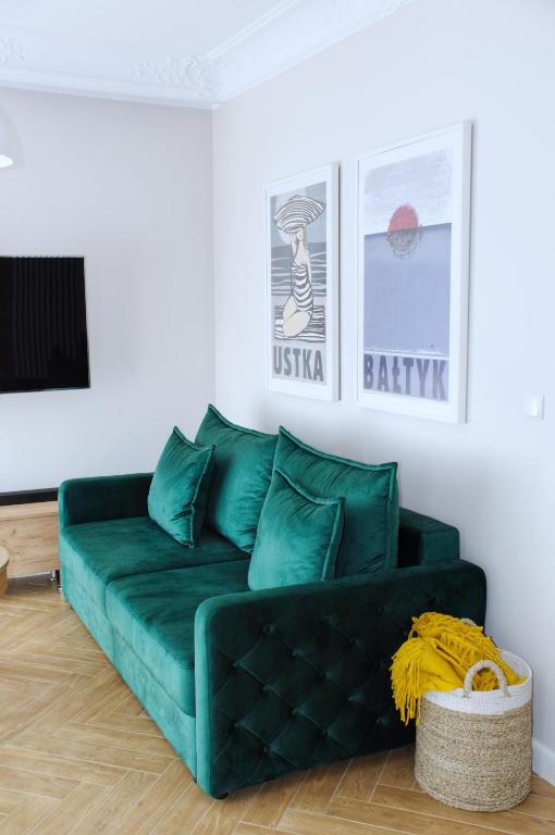 a green couch sitting in a living room at Apartamenty na skraju lasu in Ustka