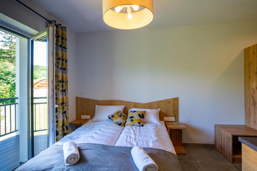 Bright bedroom with two single beds pushed together, open balcony door, geometric curtains, rolled towels