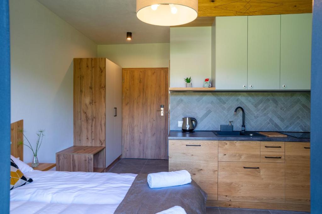 Studio bedroom with bed and rolled towels, wood-finish kitchenette, wardrobe and entrance door visible