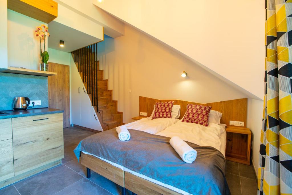 Cozy loft bedroom with double bed, folded towels, wooden stairs to upper level and patterned curtains