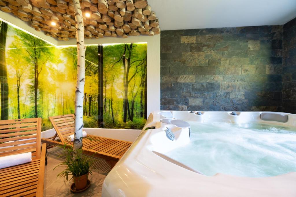 Indoor spa with bubbling hot tub, wooden loungers, birch trunk and forest mural, relaxing atmosphere