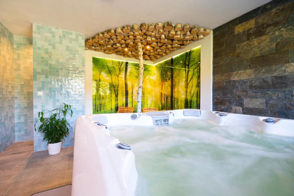 a bath tub in a room with a painting at Aparthotel Pod Stokiem z sauną i jacuzzi - szczyrkapartamenty in Szczyrk