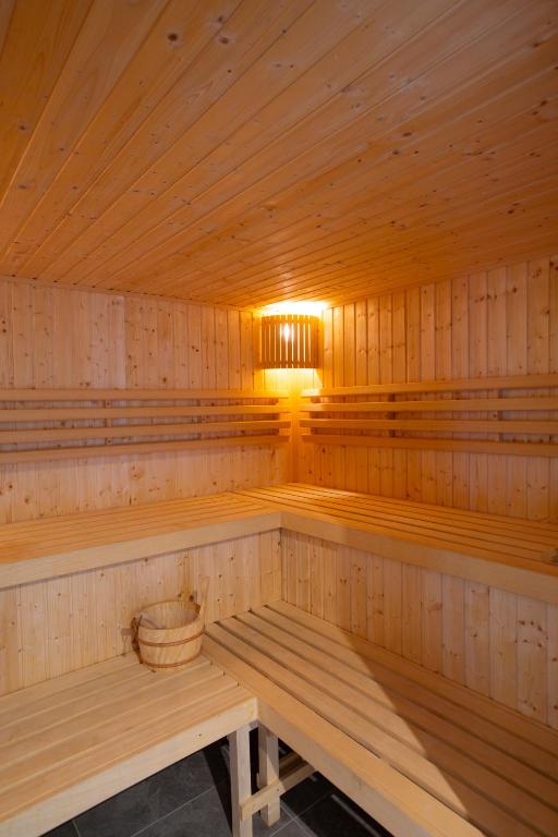 Warm wooden sauna interior with tiered benches and a wooden water bucket under soft lighting.