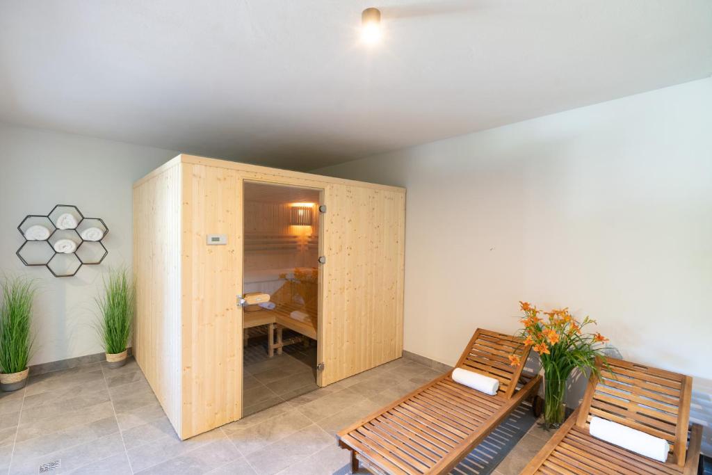 Small wooden sauna cabin in spa room with two wooden loungers and rolled towels.