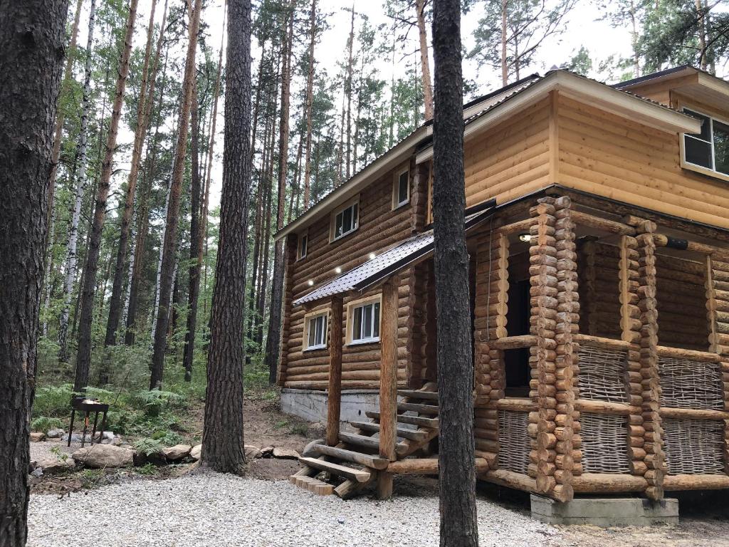 eine Blockhütte im Wald mit Bäumen in der Unterkunft Cottage Kisegach in Tschebarkul