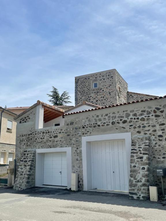 un edificio de piedra con dos puertas blancas de garaje en La Tour de l'Hirondelle, en Lussas