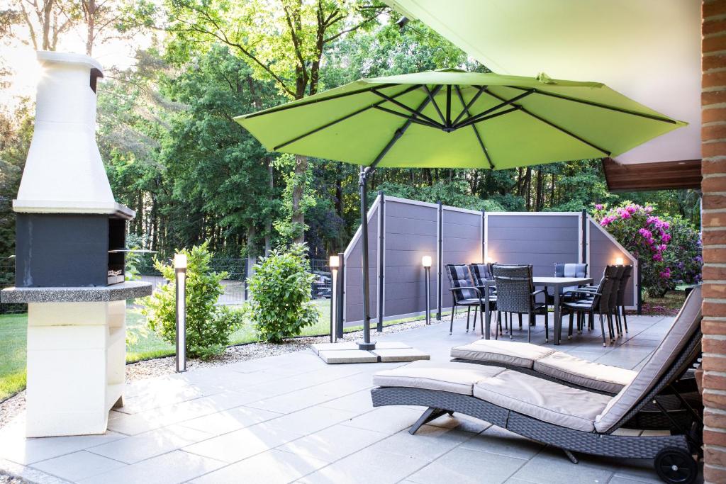 a patio with a table and a green umbrella at Lüneburger Heide - Ferienwohnung am Höpen in Schneverdingen