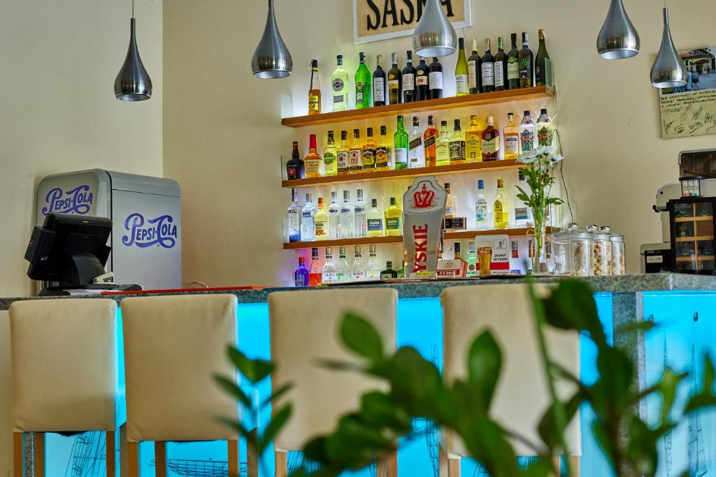 Contemporary bar interior with illuminated blue counter, leather stools, pendant lights, and shelves stocked with spirits.