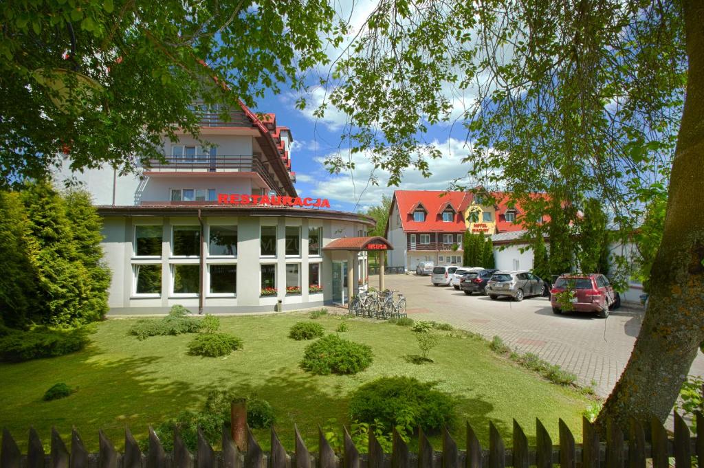 Hotel and restaurant exterior with landscaped lawn, parked cars, bicycles, and leafy trees