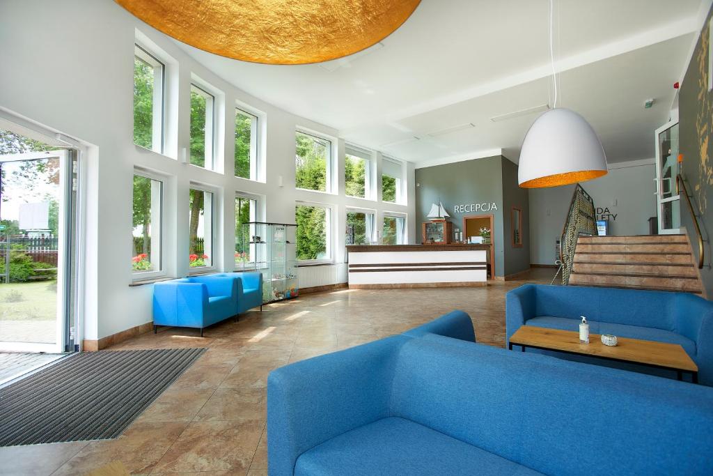 Bright hotel lobby with blue sofas, large windows, reception desk, modern pendant lighting.