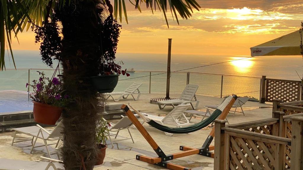 a patio with chairs and a hammock and the ocean at Green Hills Batumi in Batumi