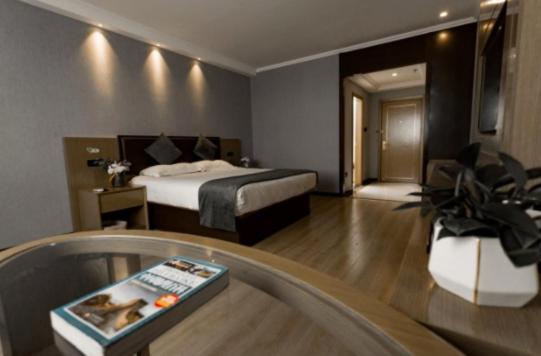 una camera con letto e un soggiorno con tavolo di GreenTree Inn Jiangsu Suzhou Changshu Fuchunjiang International Qipeicheng Road Express Hotel a Changshu