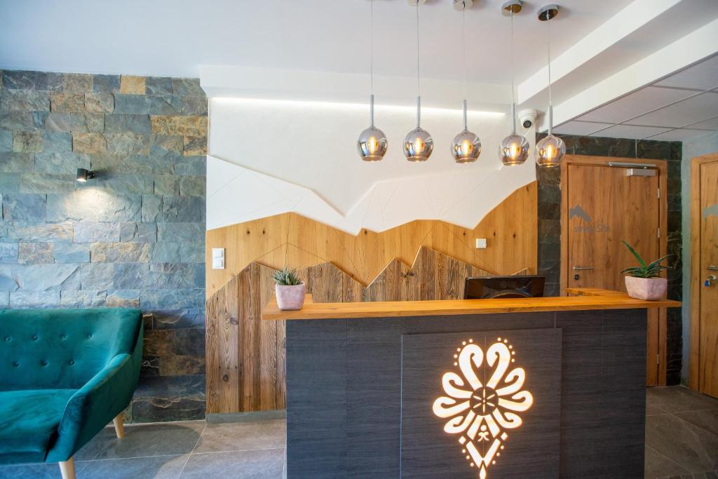 Reception area with illuminated wooden desk, pendant lights, stone accent wall and teal sofa seating